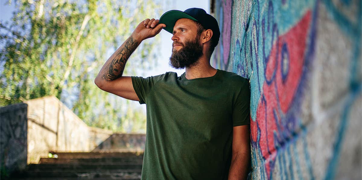 guy standing near wall wearing hat