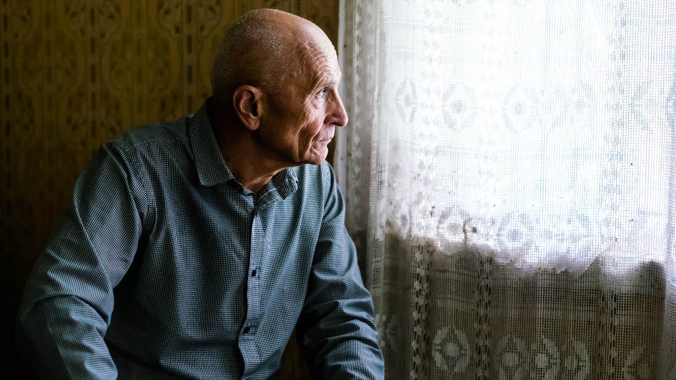 lonely old man looking out a window