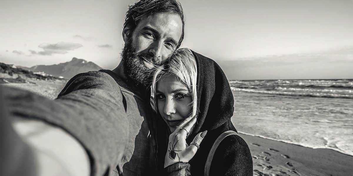 man taking photo with woman on beach
