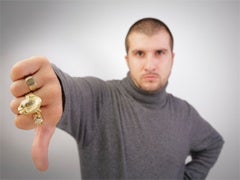 thumbs down from a man wearing a turtleneck and gold rings