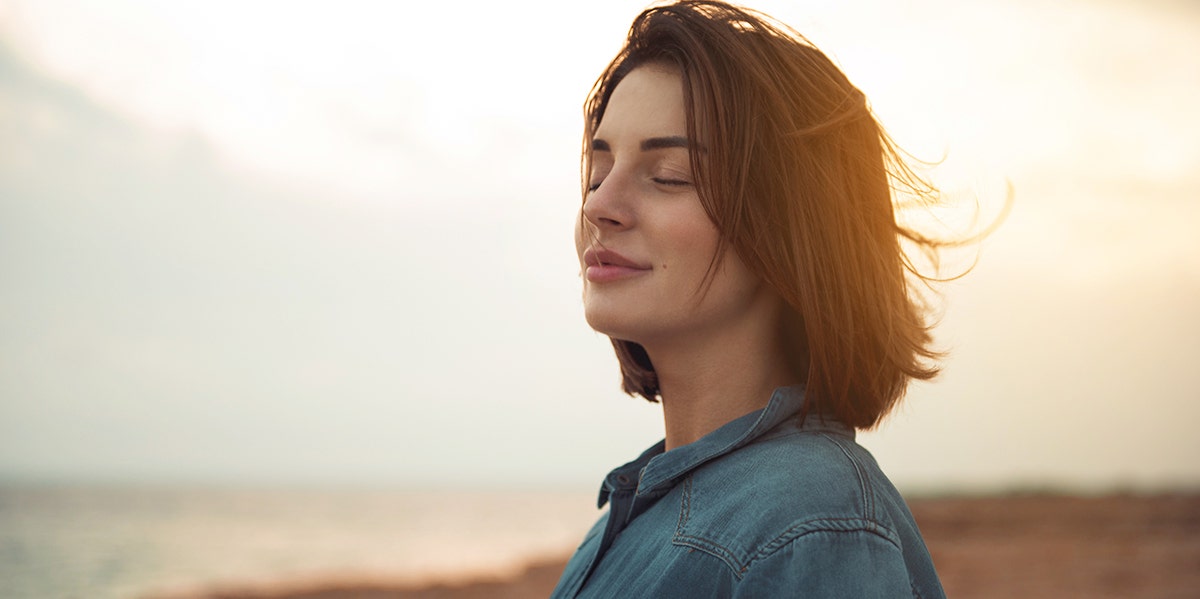 woman looking out at world with sunset behind her