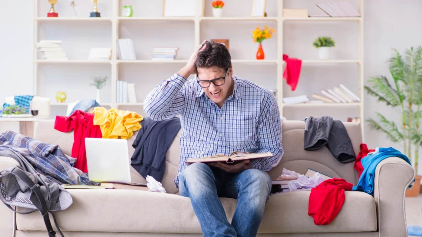 man sitting on a couch in a messy room