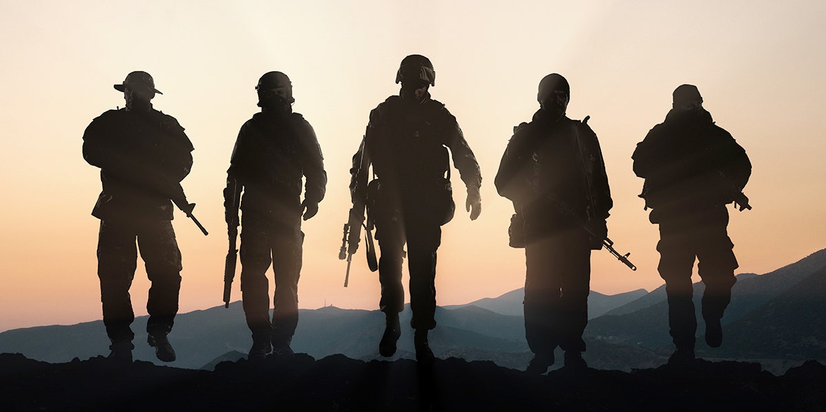 Silhouette of military members against a sunset