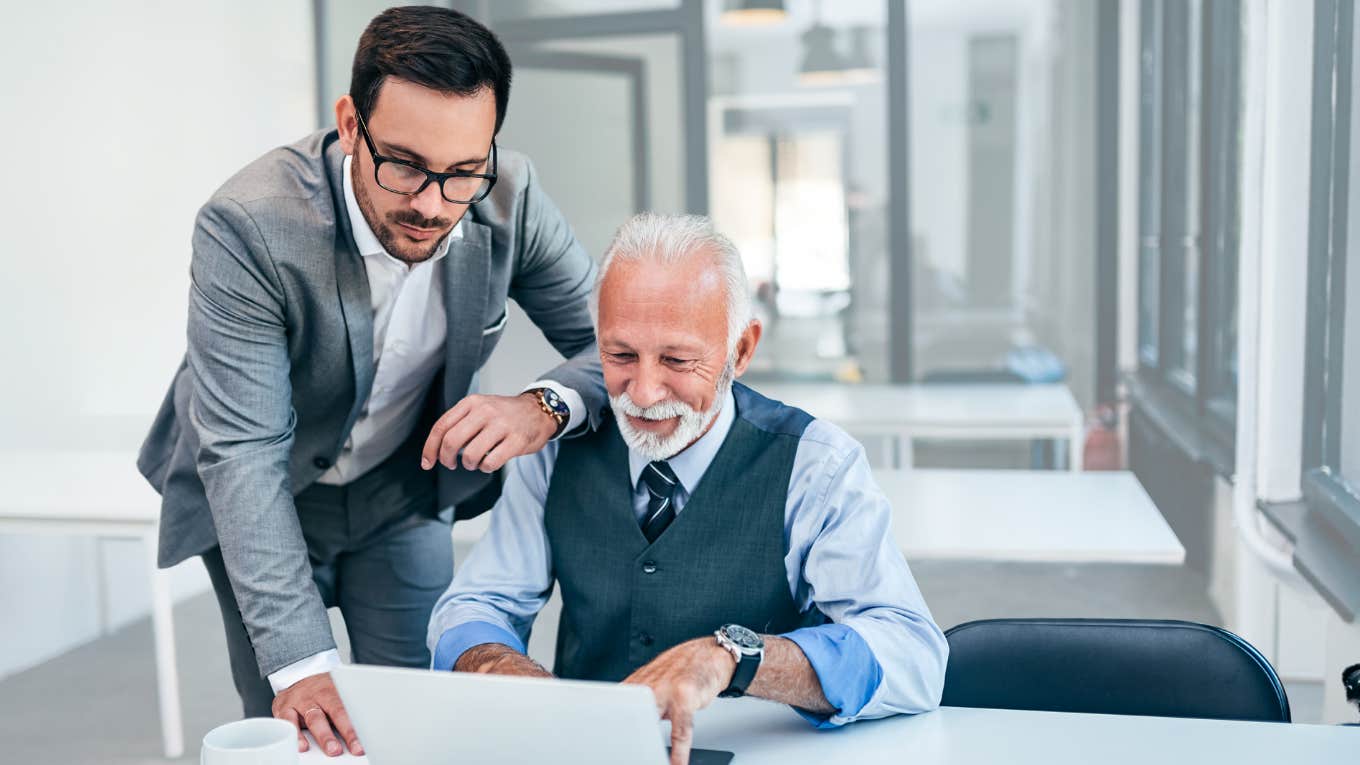 Boss helps older employee with his computer. 