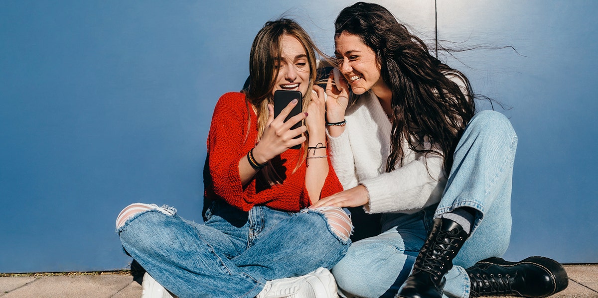 young girls looking at the phone laughing