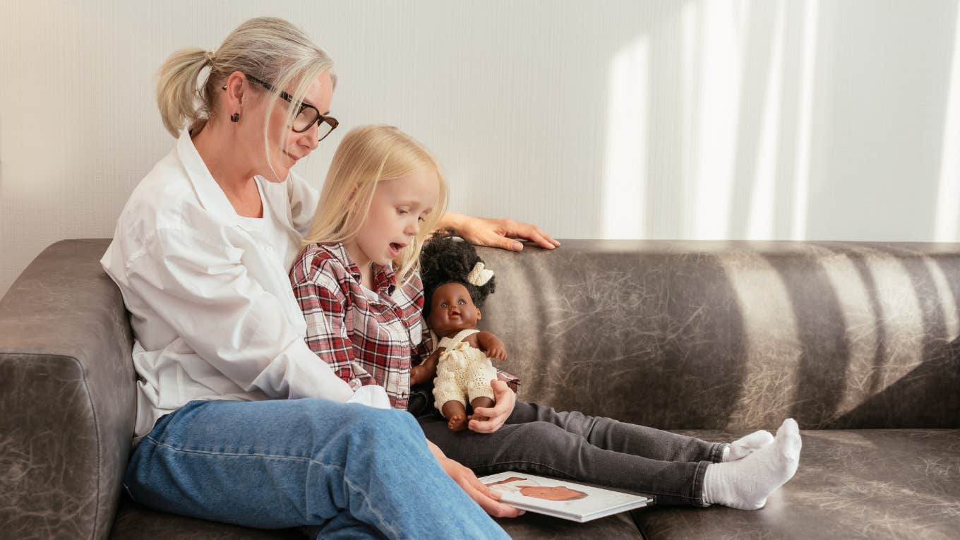 grandmother reading a book to her granddaughter on a couch