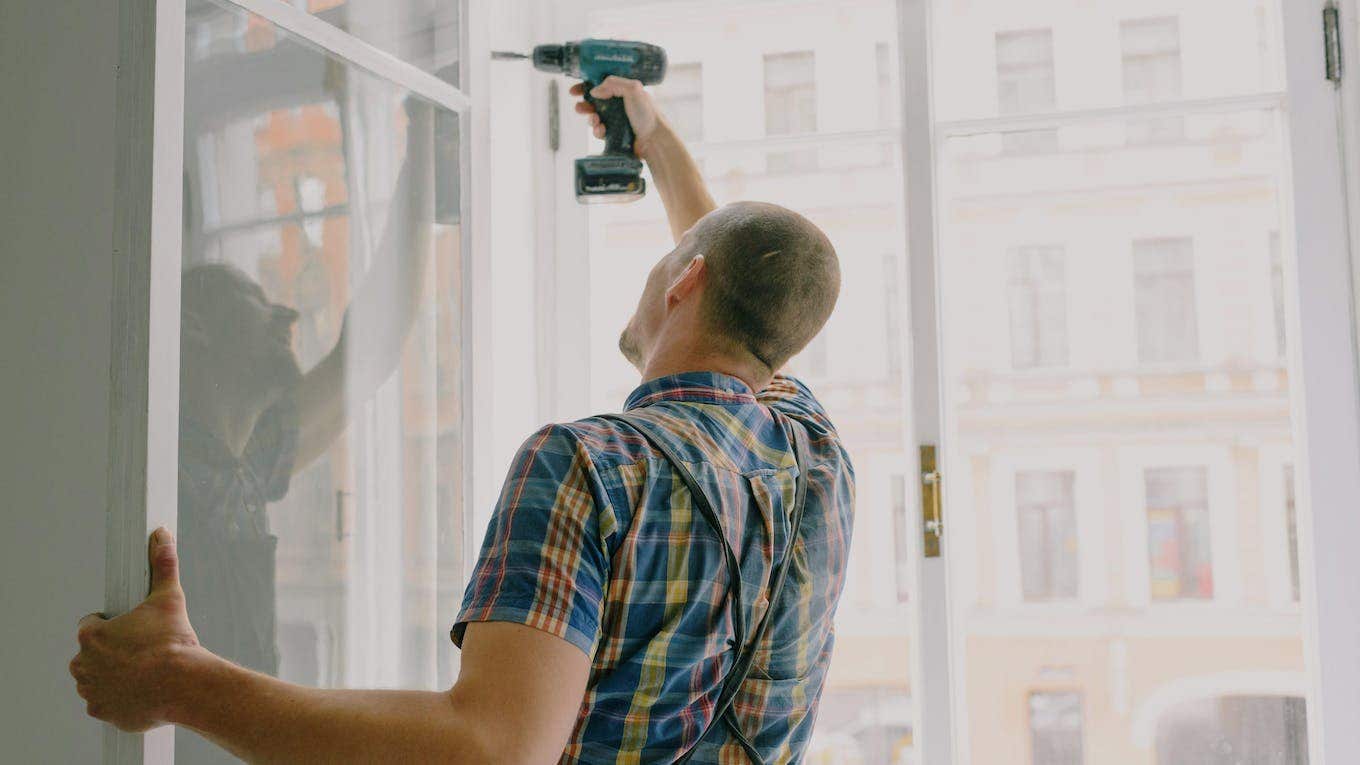 man building a home drilling window