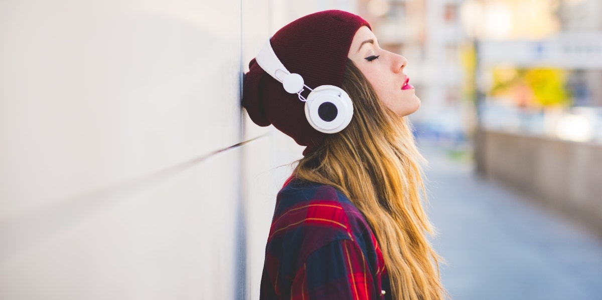 woman wearing beanie and headphones leaning on wall 