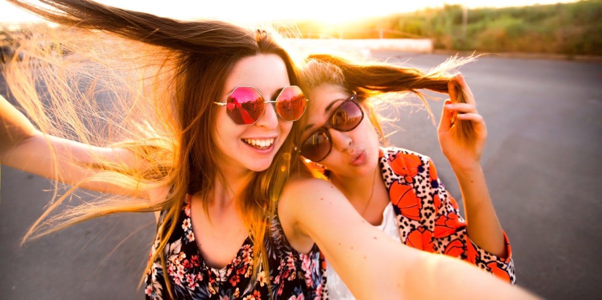 two friends in sunglasses smiling laughing