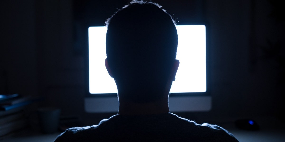 What Is The Difference Between Misinformation Vs. Disinformation? silhouette of man sitting in front of a lit computer screen
