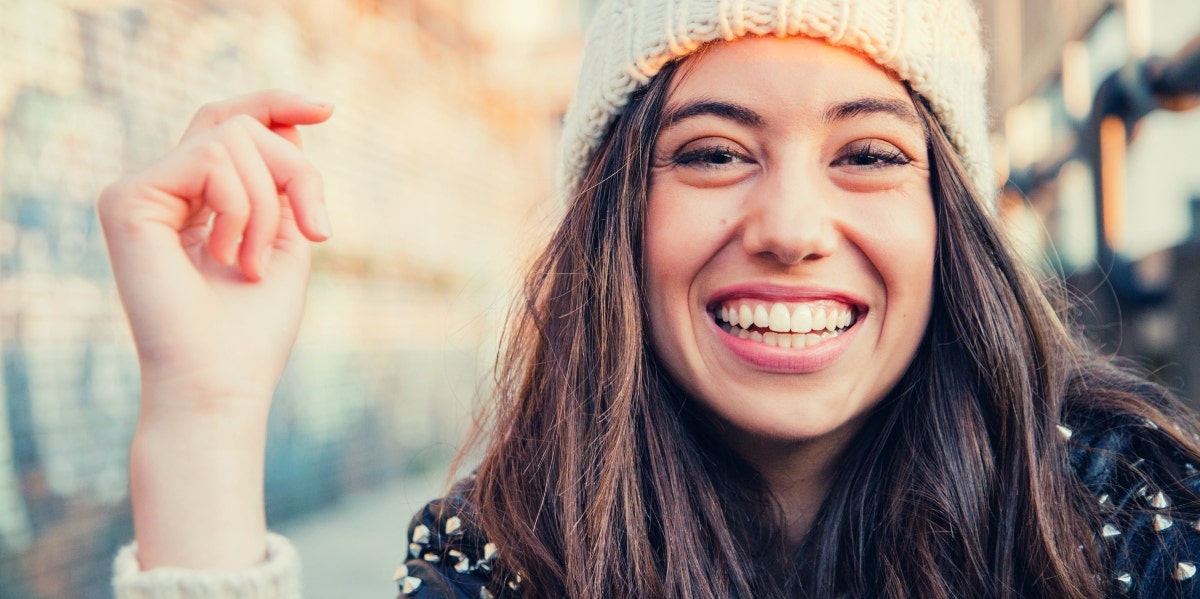 happy woman in knit beanie under the sun