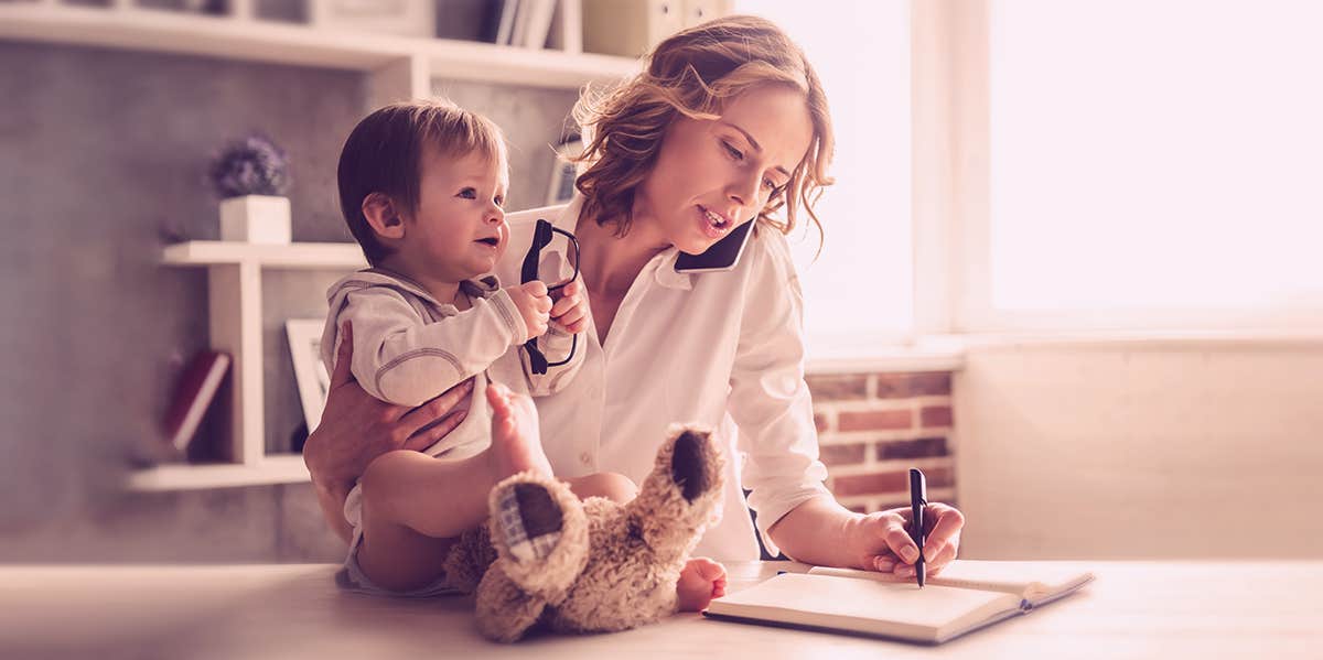 mom holding her child while working