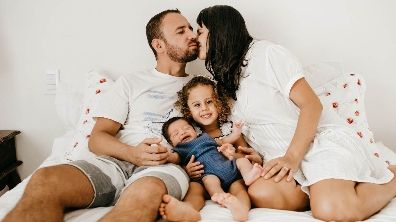 mom, dad, and two kids on a bed