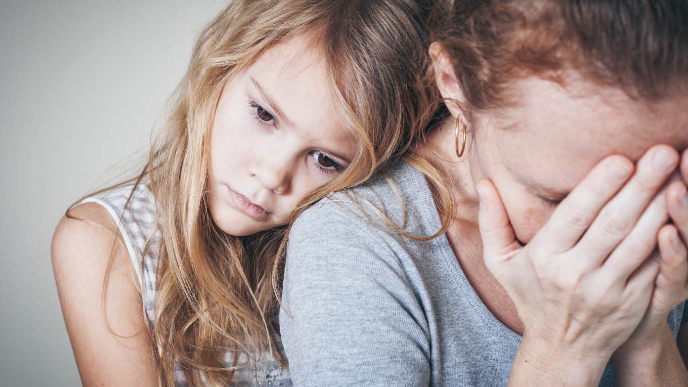 sad daughter hugging her upset mother who is covering her face