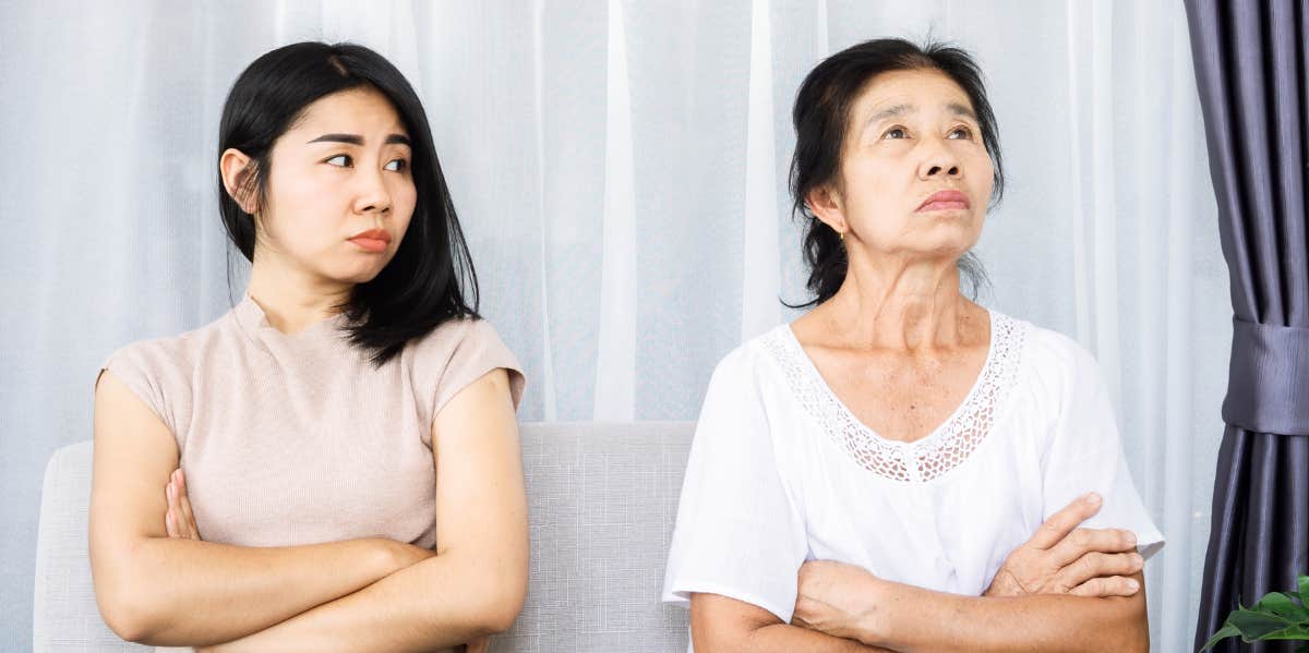 Two women with their arms crossed are angry at each other.