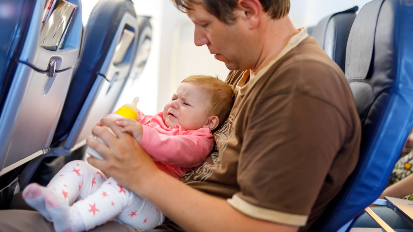A man holds a crying baby on a plane