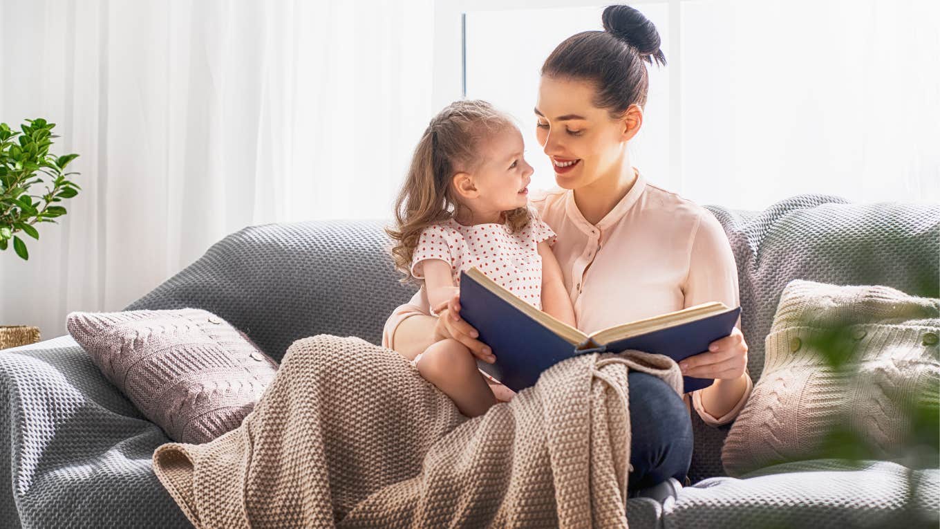 mother reading to toddler on couch
