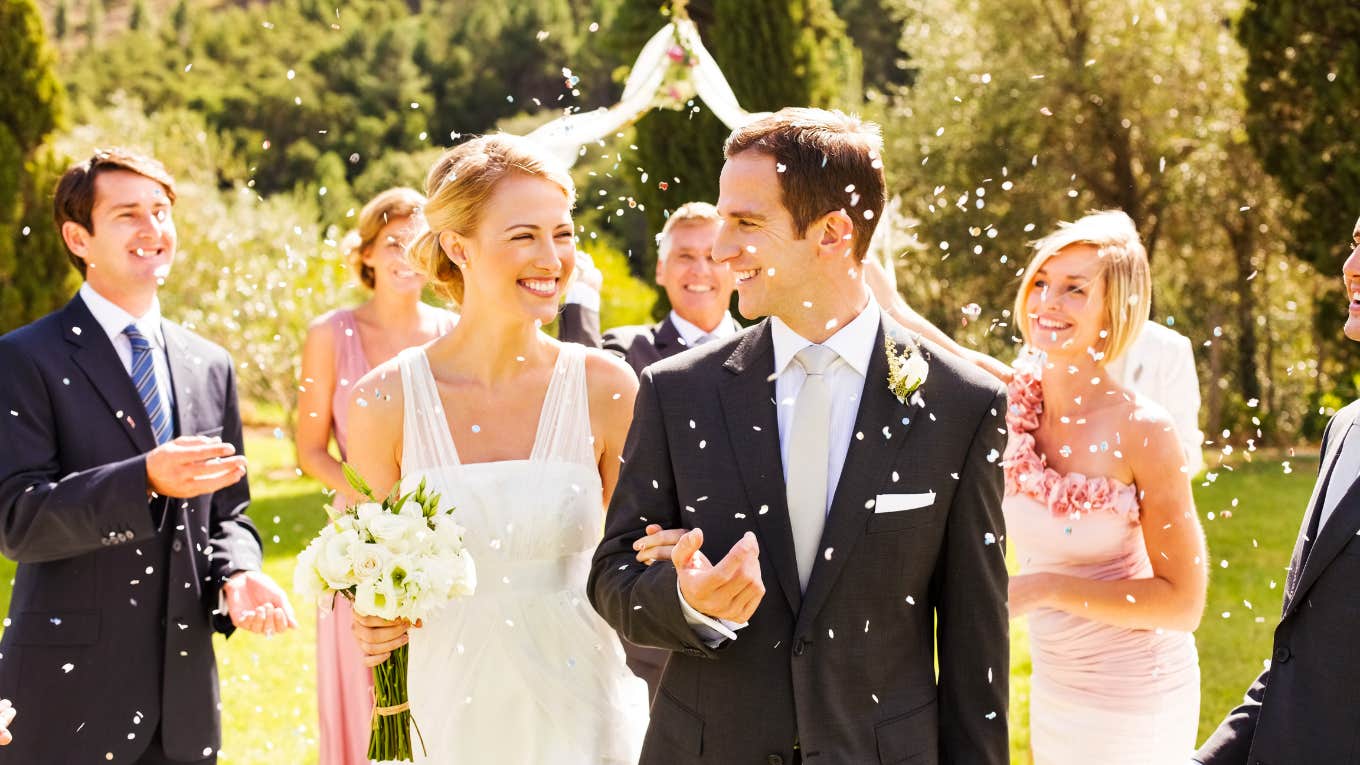 Guests Throwing Confetti On Couple During Garden Wedding