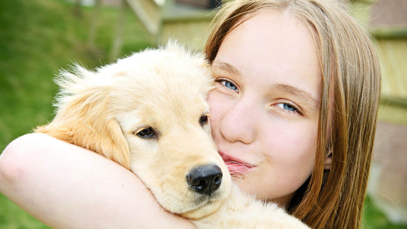 teenage girl holding and kissing a dog