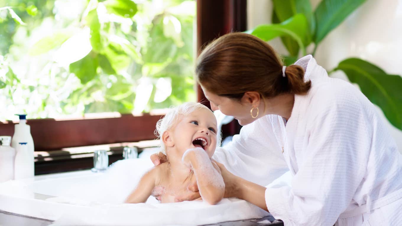 mom helping toddler take bath