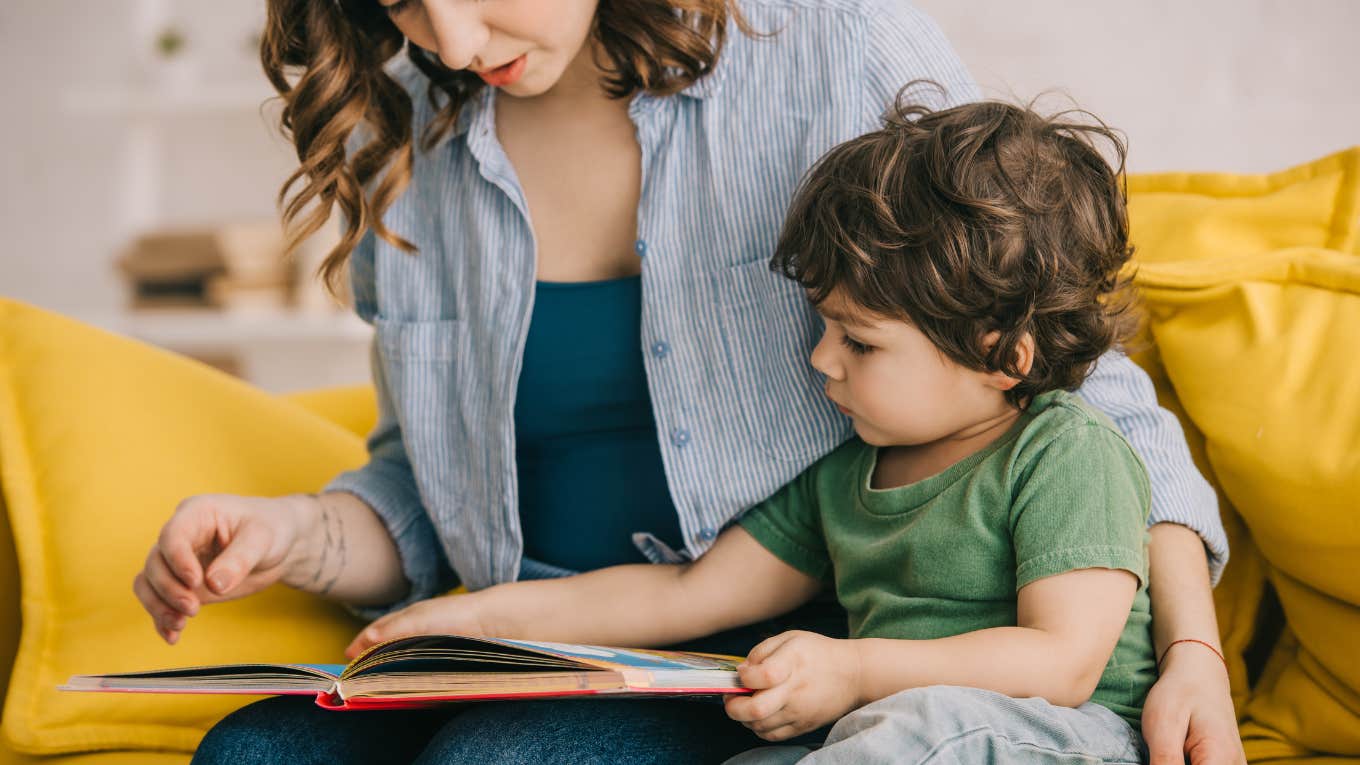 Cropped view of mother and son reading book together on couch at home