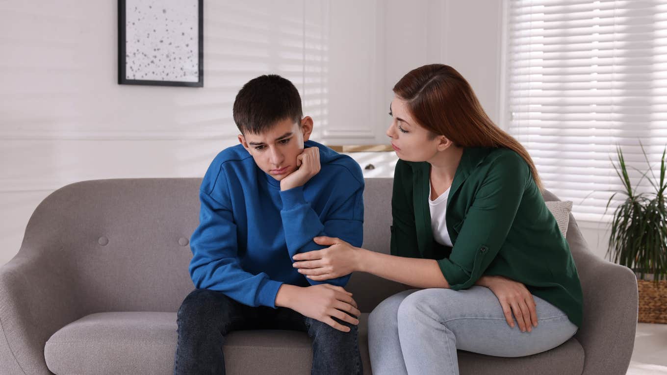 mom consoling her upset son while sitting on a couch at home