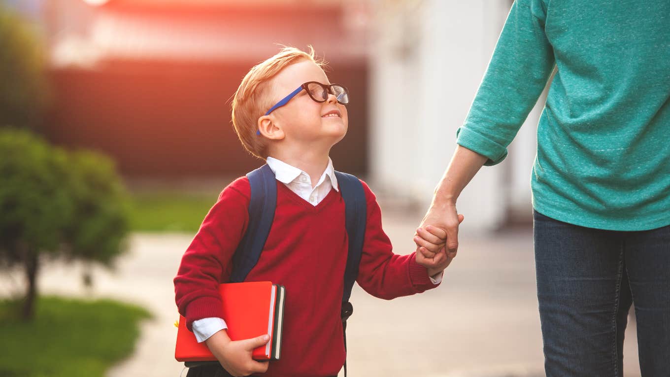 little boy holding mom's hand walking to school