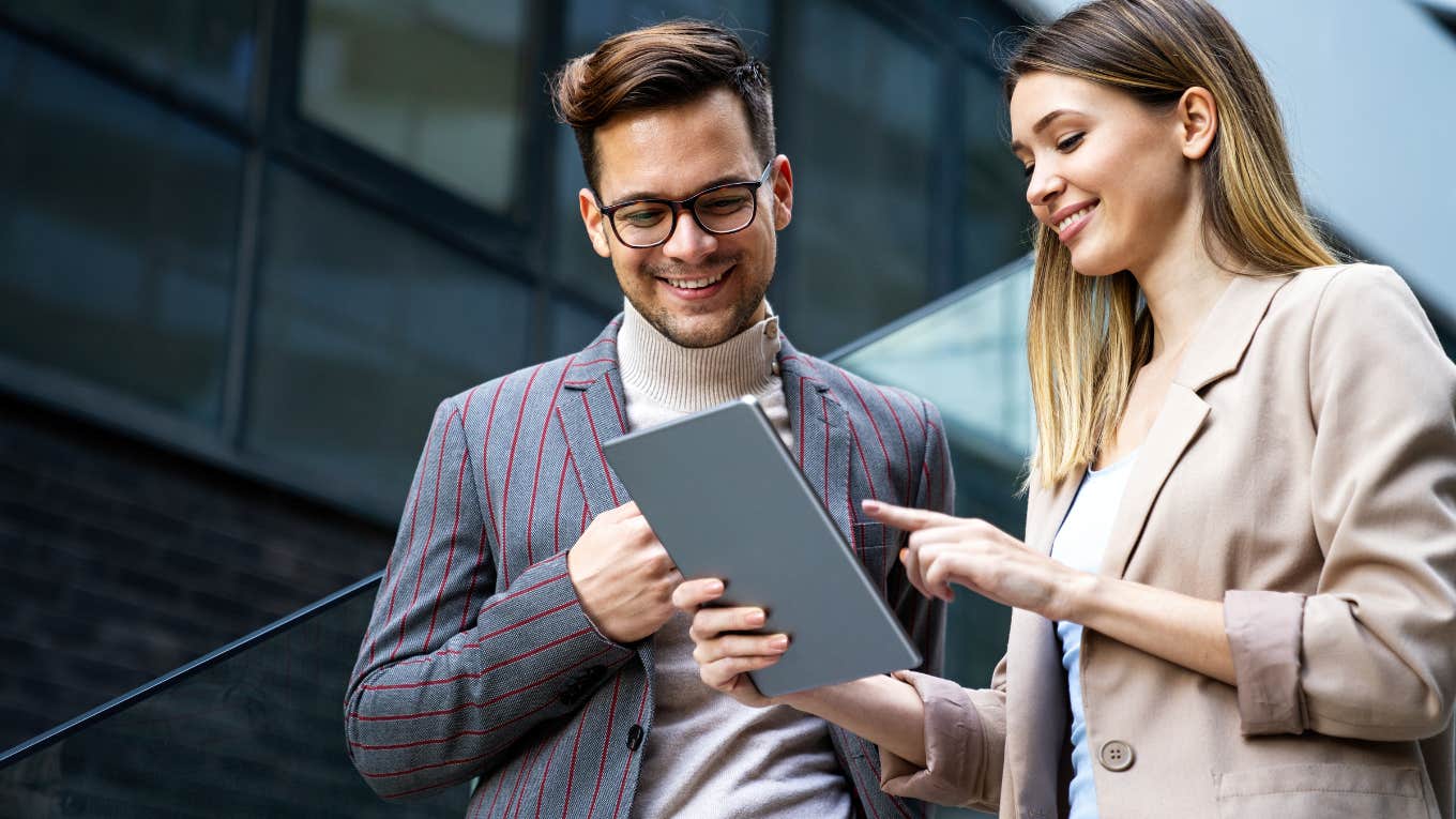 Portrait of successful business people working, talking together while looking at tablet