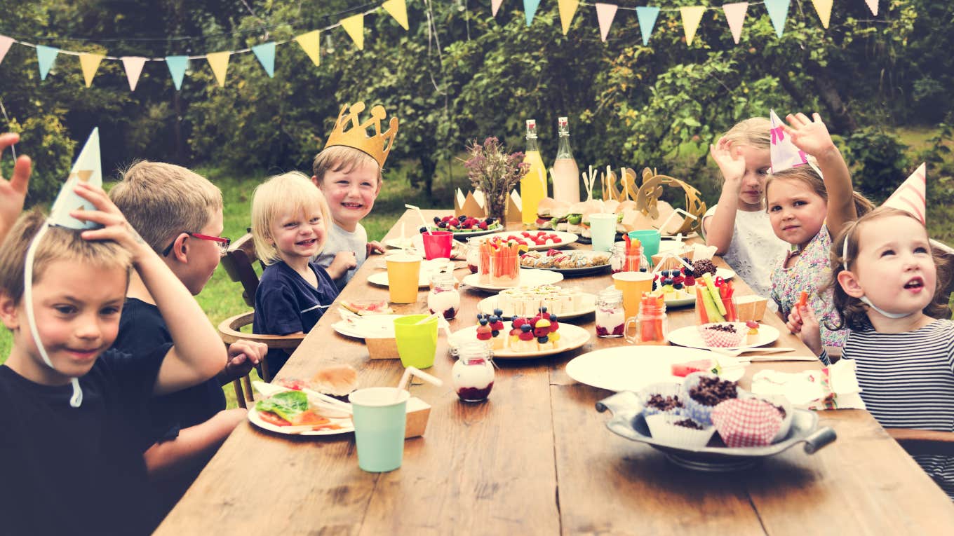kids sitting around table with birthday hats at party