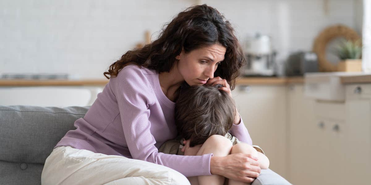 Worried mother hugging her son on the couch.