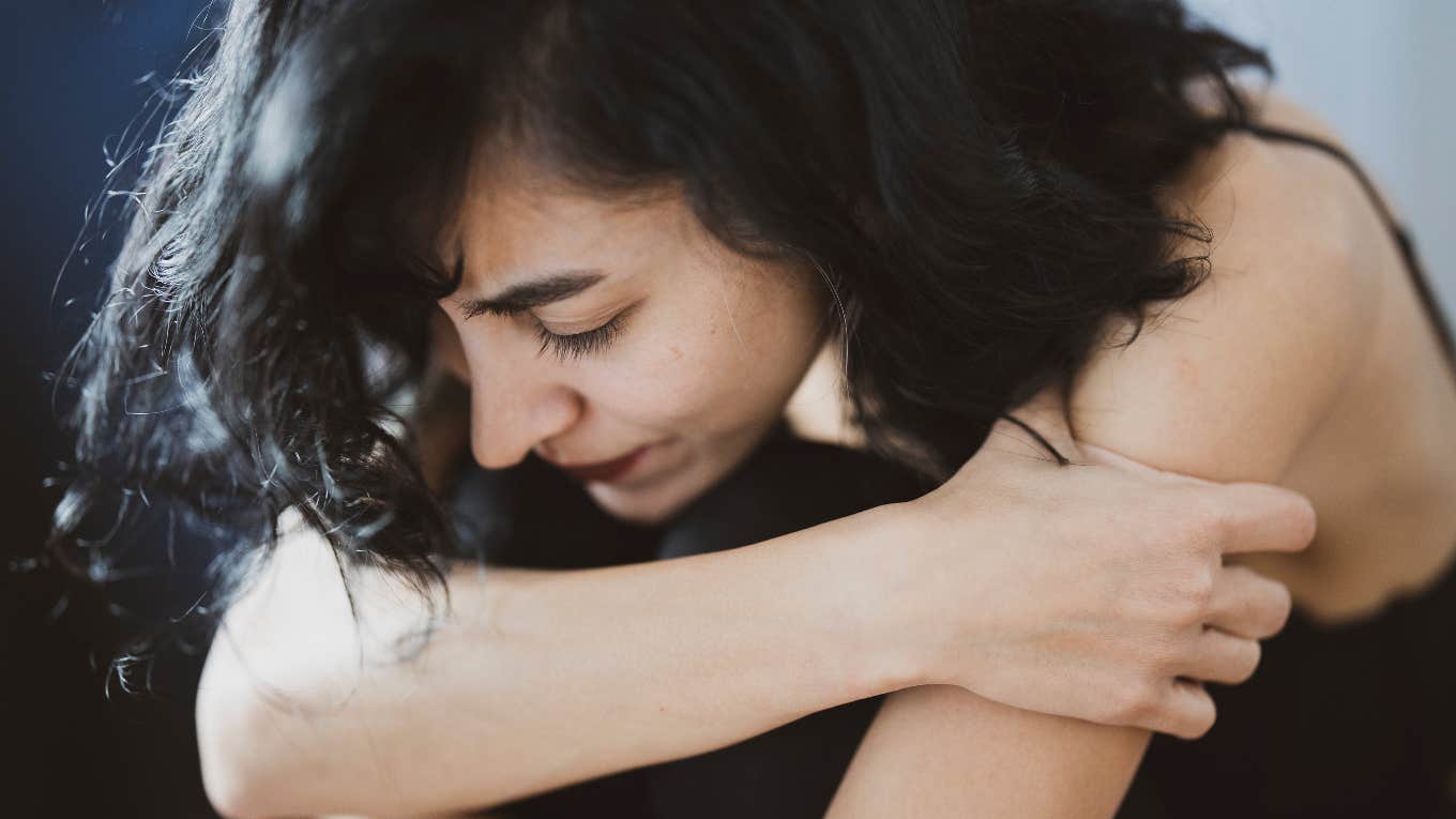 upset woman crouching and hugging her legs