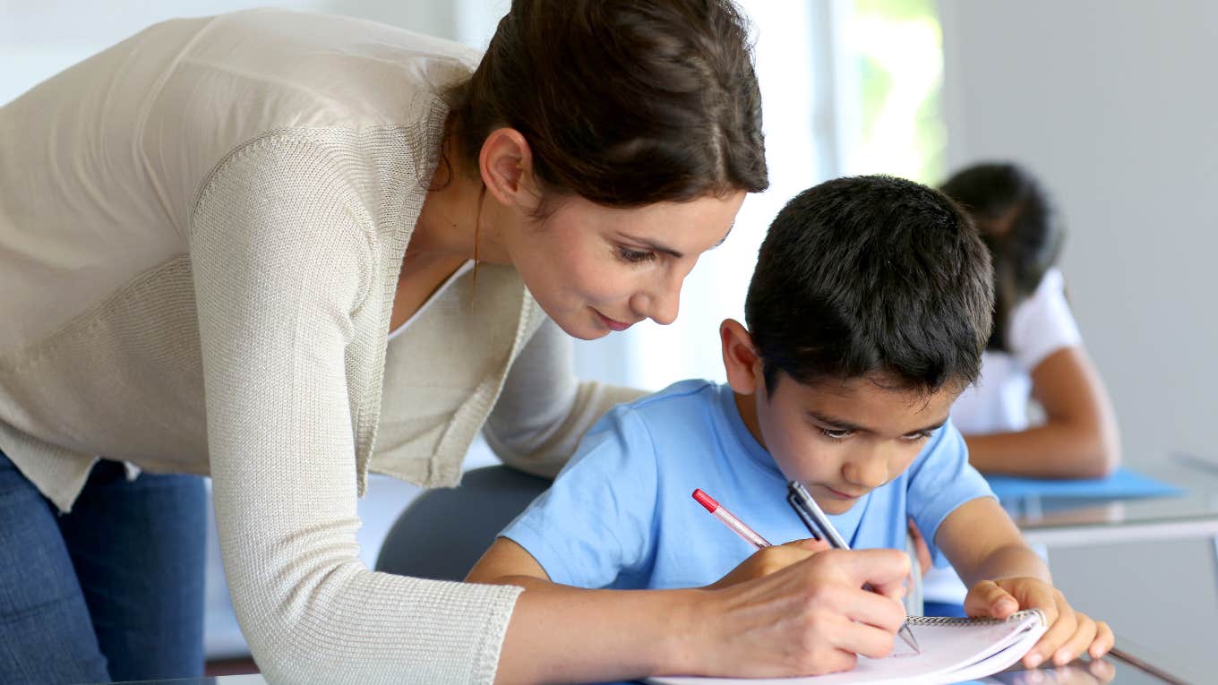 Teacher helping young boy with writing lesson