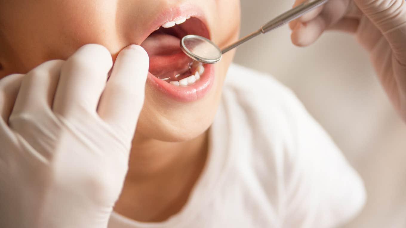 close up shot of child's teeth being examined with tools by dentist