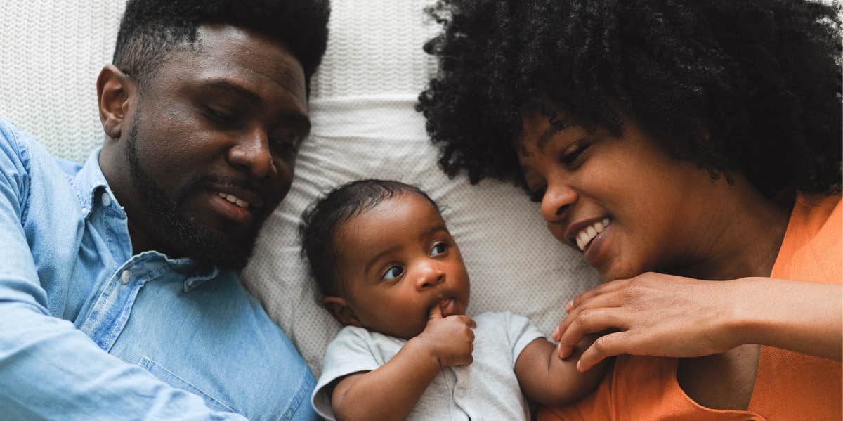 Mom, dad, and baby lying on bed 