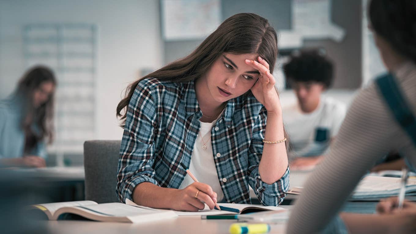 Mom Says She Was Shocked After Her Daughter's Teacher Told Her To Hold In Her Period Until Class Ended anxious teen girl with hand on head sitting in class
