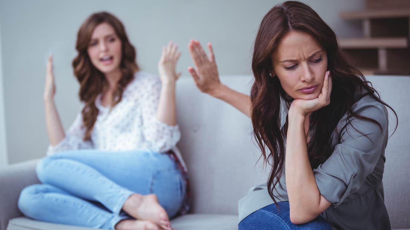 two women sitting on a couch arguing with each other