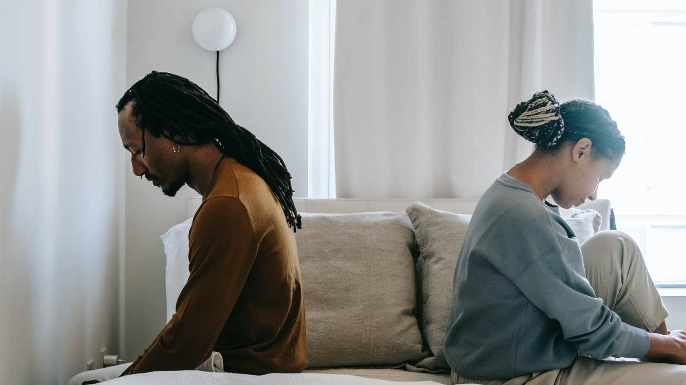 man and woman sitting back to back on a bed