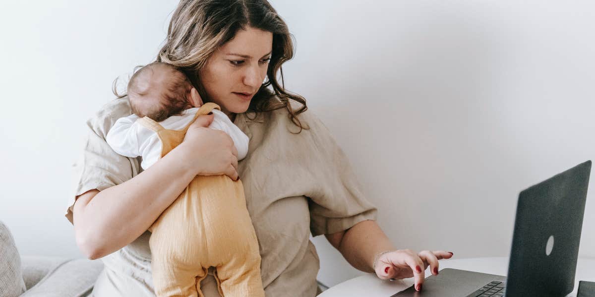 Mom holding baby while working on computer