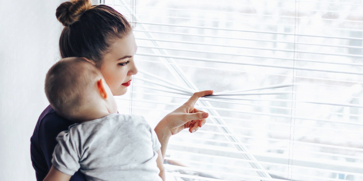 I Didn't Want To Be A Mom, But Had Kids Anyway woman holding baby looking out window