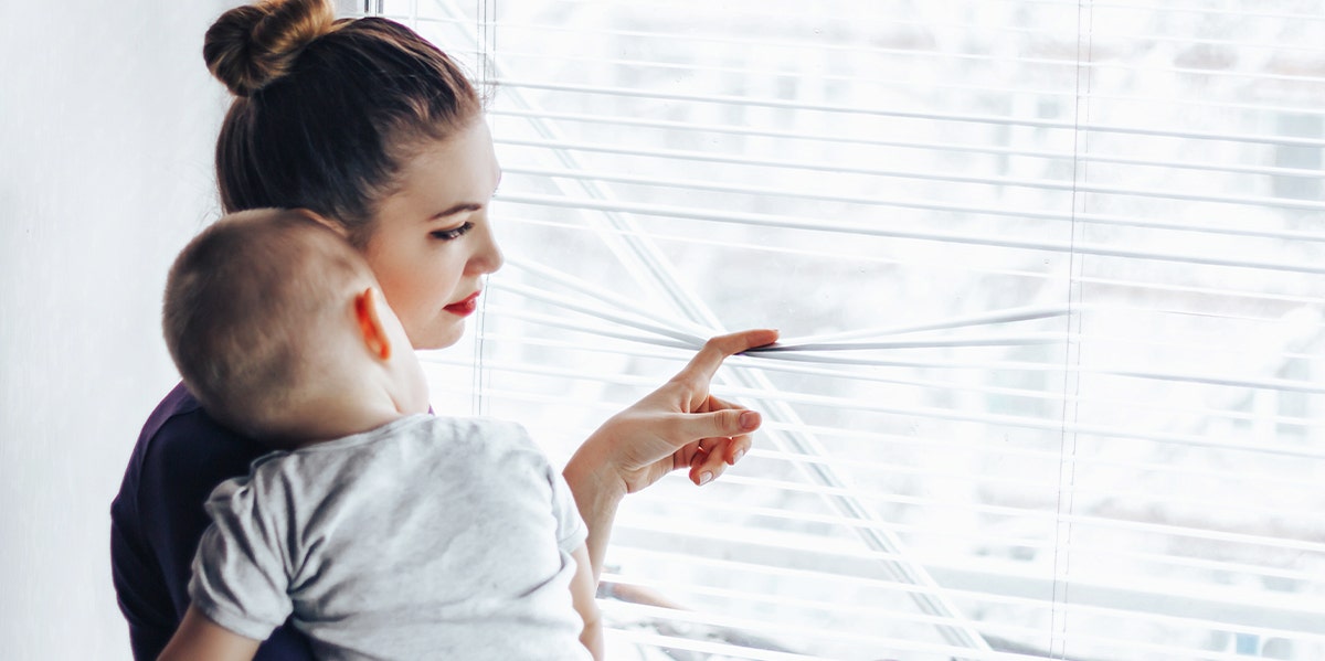 woman holding baby looking out window