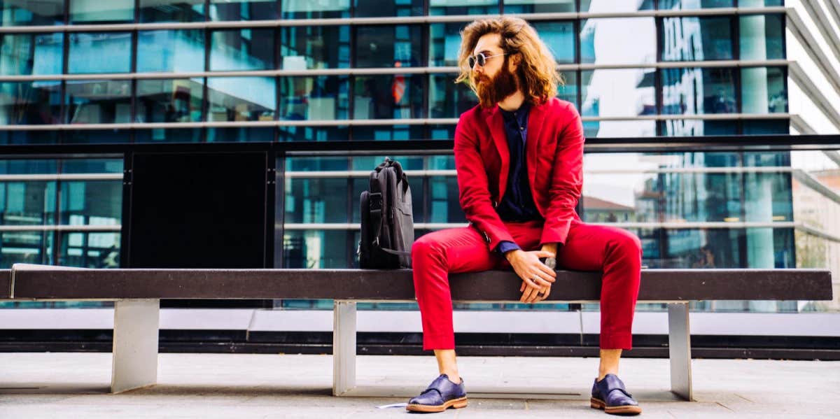 man in red suit sitting on a bench outside