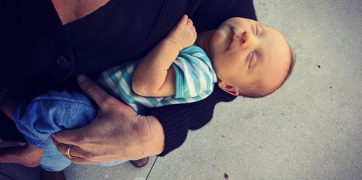 A woman's arm holding a newborn baby, both caucasian 