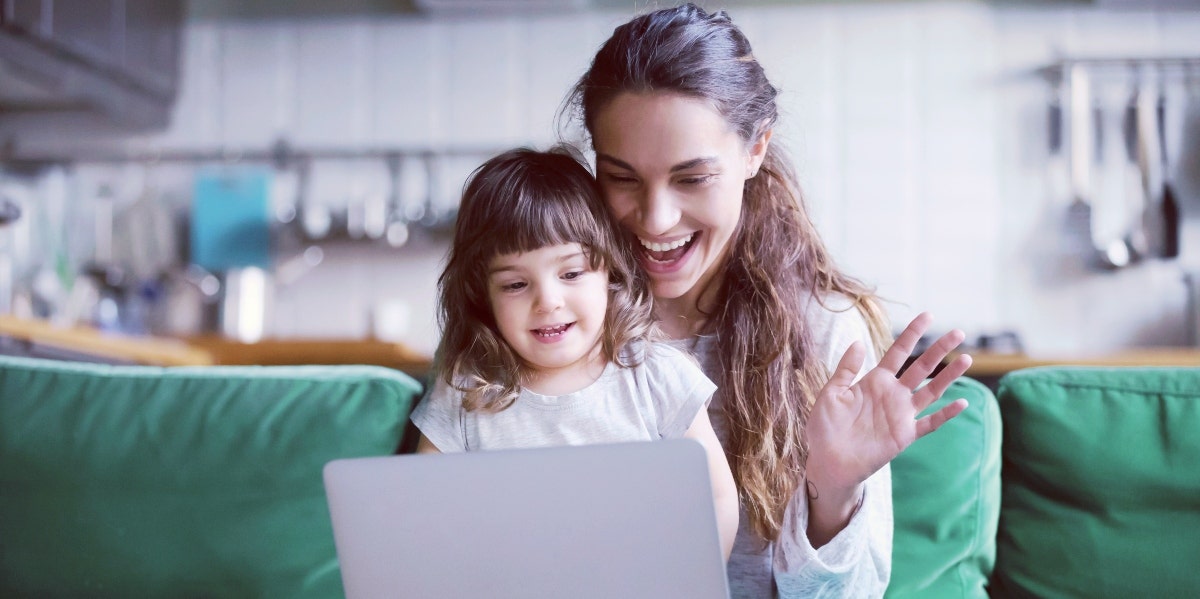 moms dread return to pre-covid times woman with little girl on her lap waving at a computer