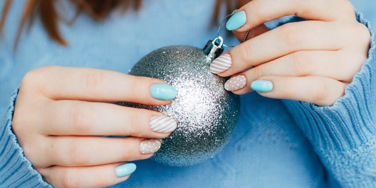 woman with manicure holding christmas ornament