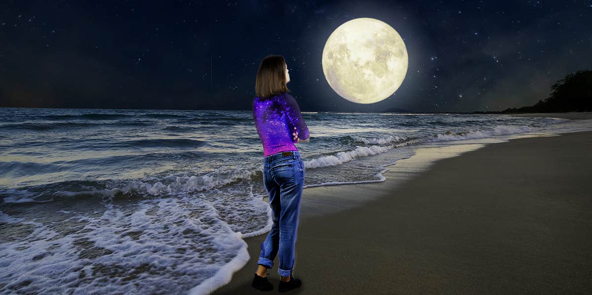 woman on the beach looking at the moon