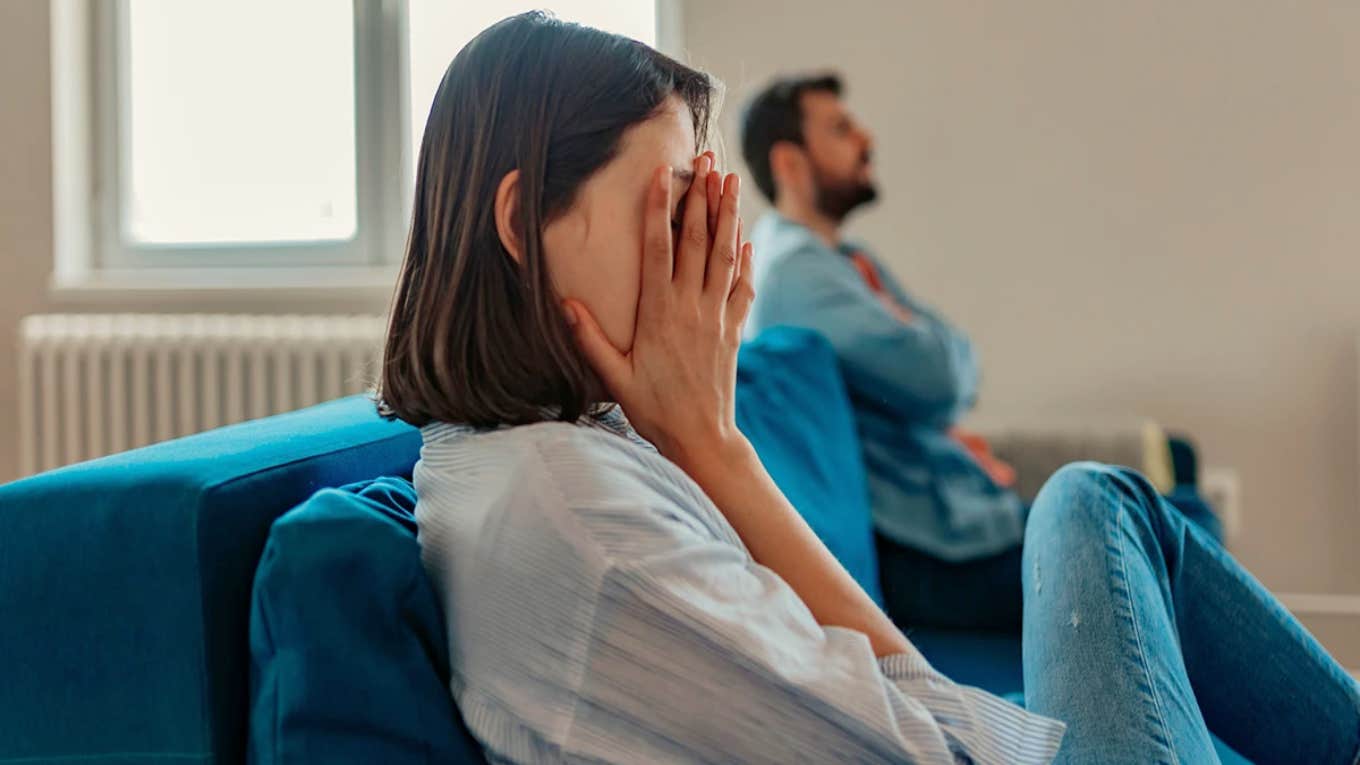 sad woman sitting on couch with man in background