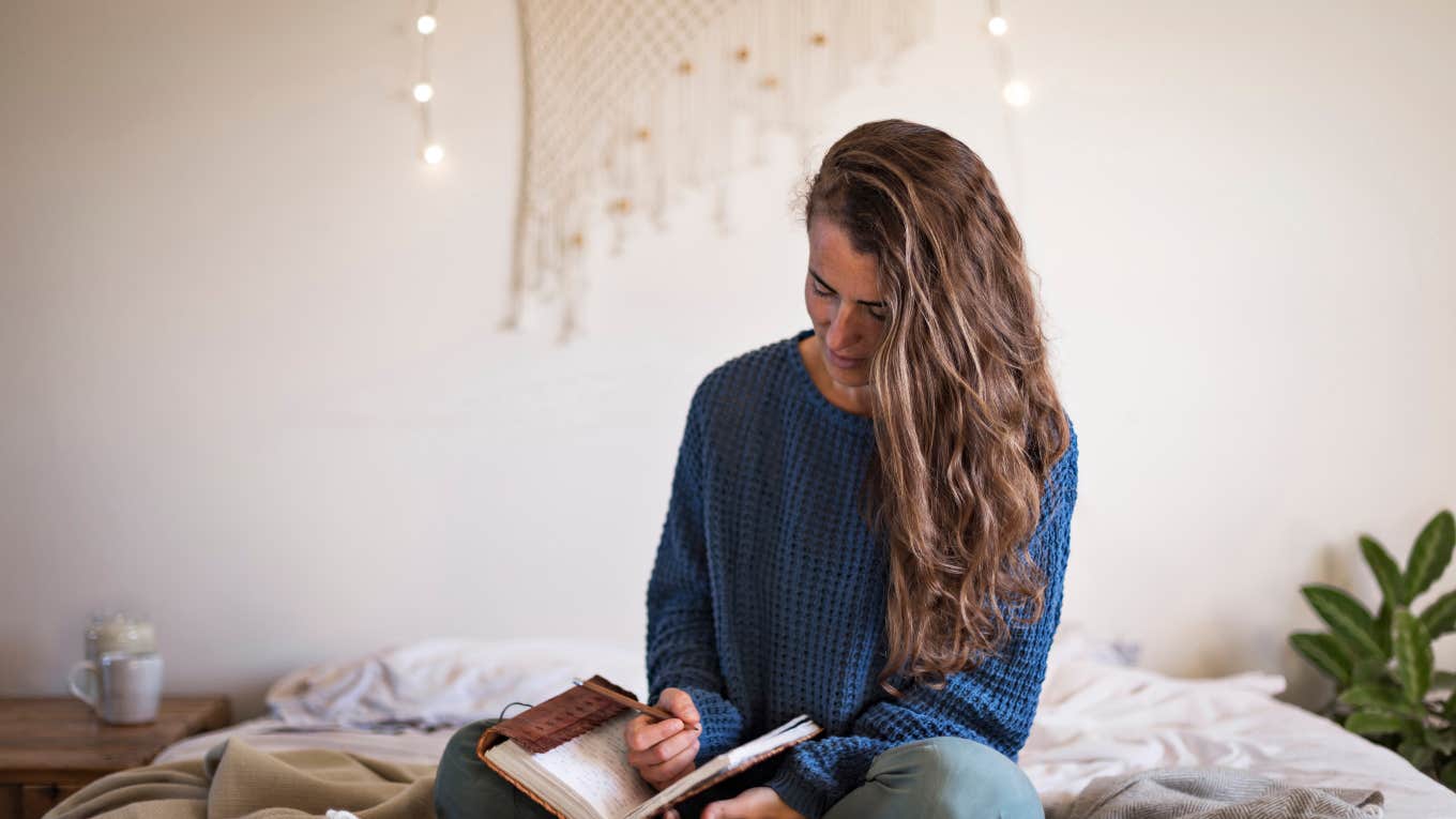 woman sitting on bed journaling
