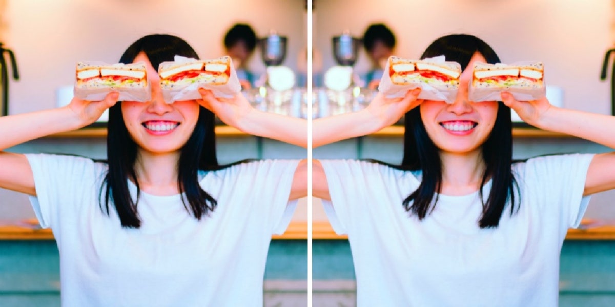 woman holding sandwich halves above her eyes