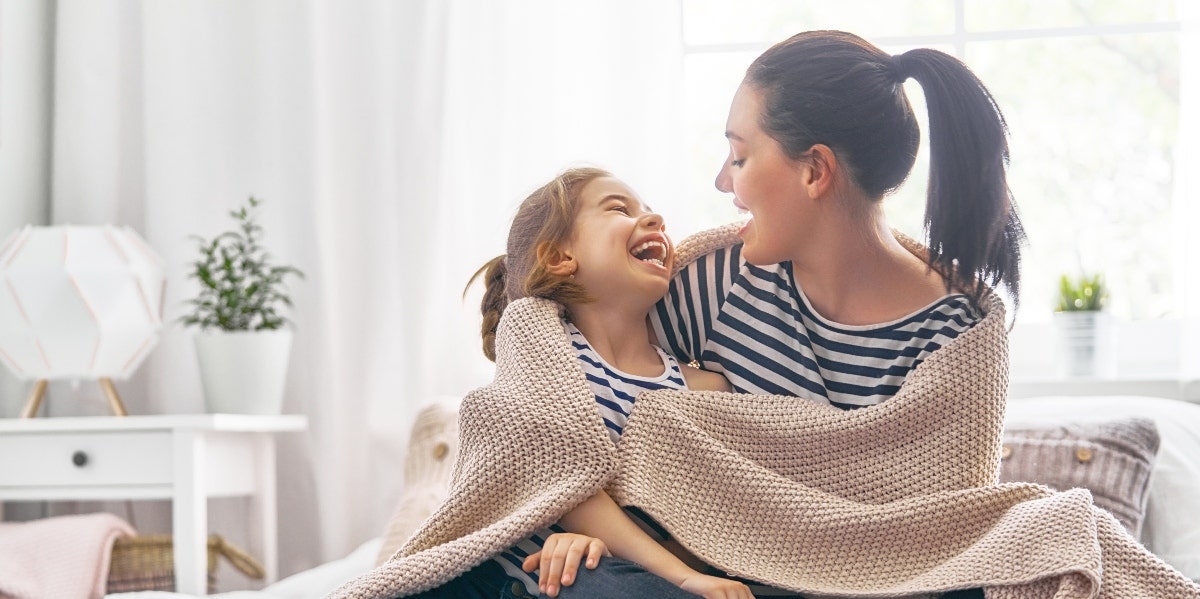 mother and daughter in blanket smiling at each other