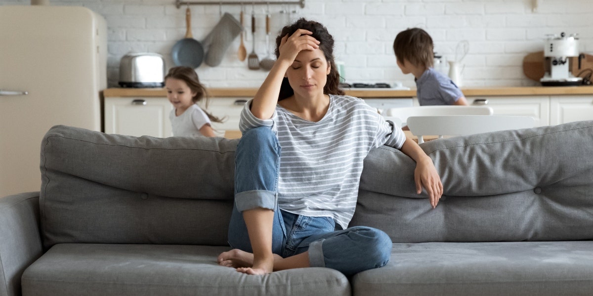 stressed mom on a couch in front of her children